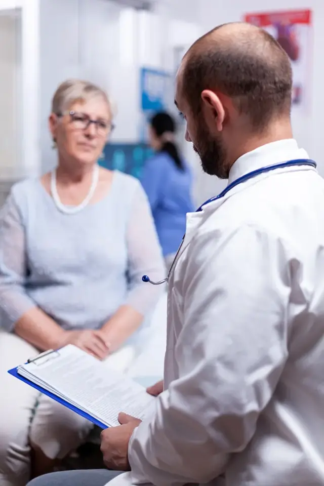 doctor holding medical document while talking elderly senior cabinet clinic